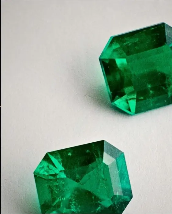 Two emerald-cut Colombian emeralds on white paper