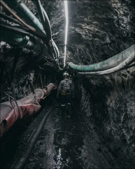 Miners inside a shored tunnel with headlamps